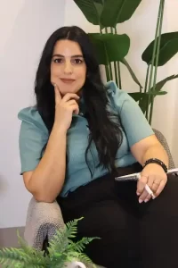 אירית שלום, מאמנת נשים לאחר אובדן, יושבת בכורסה בתנוחה מהורהרת עם יד לסנטר