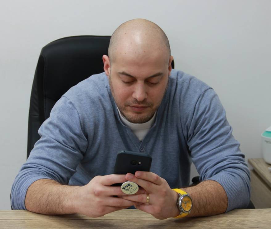 אבירם שפיץ יושב ליד שולחן ומחכה לאינסטלטור - אמון באימון